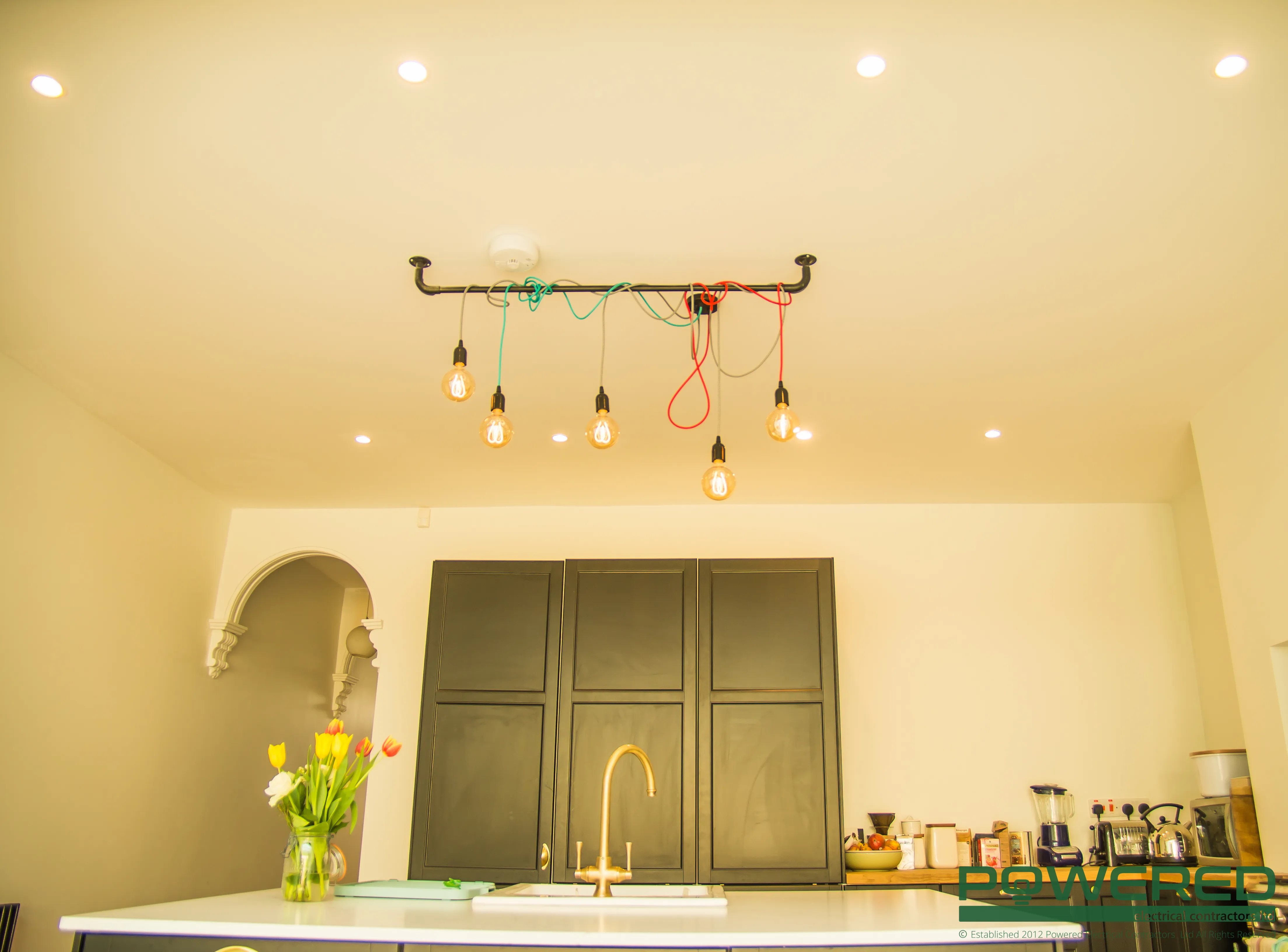 A kitchen with a sink and a bunch of lights hanging from the ceiling.
